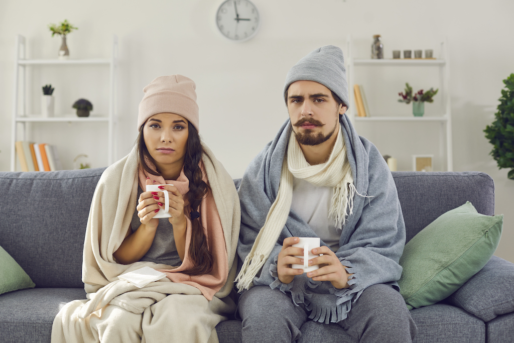Couple wearing many layers of clothing to stay warm in their home that has poor insulation